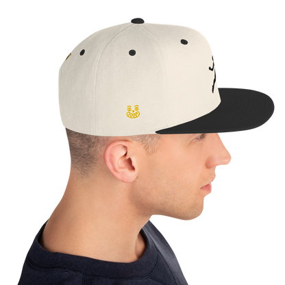 Snapback cap with off-white front panel, small yellow logo, black brim and side stitching